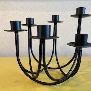 Puede incluir: Candelabro de metal negro con seis portavelas. El candelabro tiene un dise&ntilde;o curvo y abierto con un acabado mate. Los portavelas son circulares y elevados, adecuados para velas de tama&ntilde;o est&aacute;ndar. Un acento decorativo para el hogar.