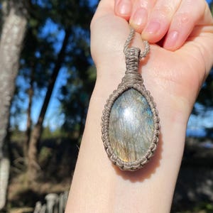 May include: A silver and blue labradorite gemstone pendant with a brown macrame cord.