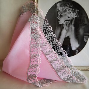 May include: A pink handkerchief with a silver lace trim. The lace is a delicate floral pattern.