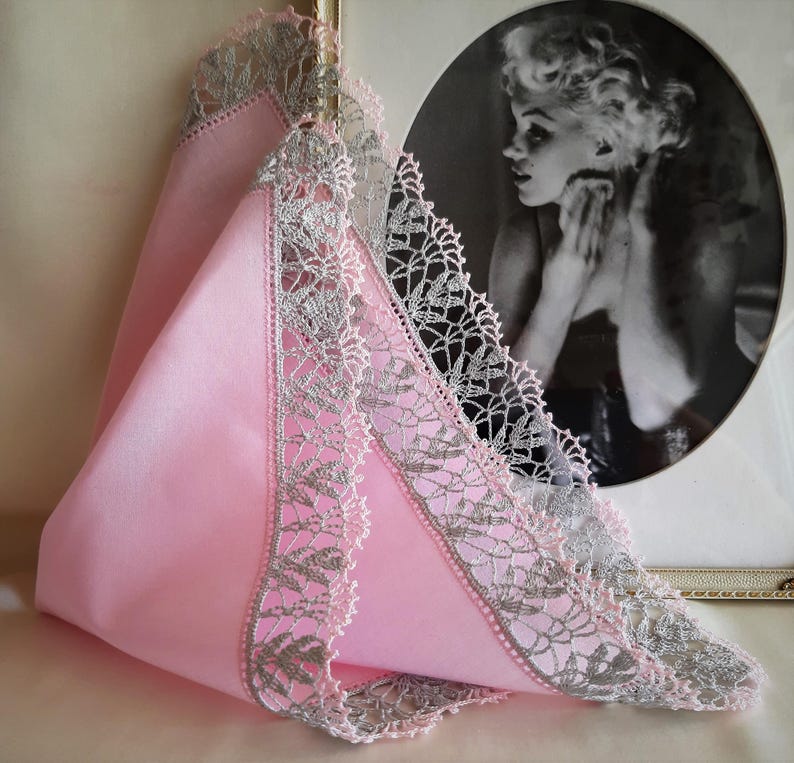 May include: A pink handkerchief with a silver lace trim. The lace is a delicate floral pattern.