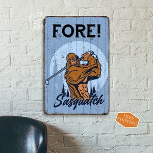 May include: A blue and white sign with the text "FORE! Sasquatch" and a cartoon image of a Sasquatch swinging a golf club.
