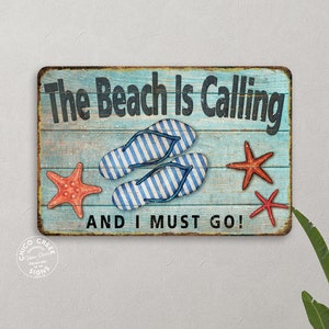 May include: A blue and white wooden sign with the text "The Beach Is Calling And I Must Go!"  The sign features two blue and white striped flip flops and three red starfish.