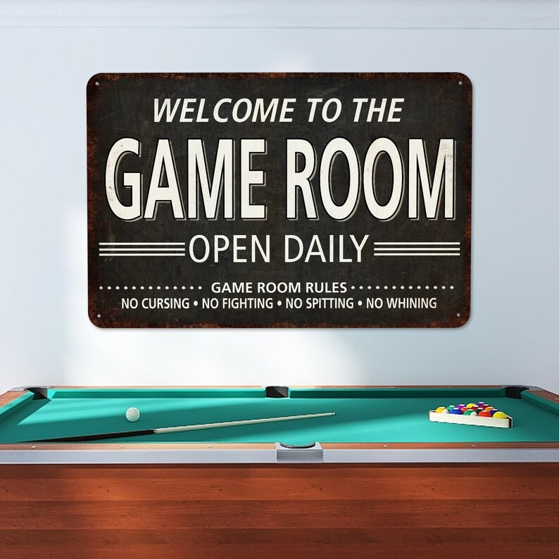 May include: A black and white metal sign with the text "Welcome to the Game Room Open Daily" and the rules "Game Room Rules: No Cursing, No Fighting, No Spitting, No Whining".