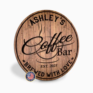 May include: Round wooden sign with the text "Ashley's Coffee Bar" in a stylish font. The sign also includes the text "Brewed with Love" and "Est. 2025". A small "Made in USA" emblem is visible at the bottom.
