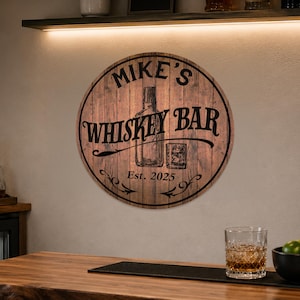May include: Round wooden sign with the text "Mike's Whiskey Bar" in black lettering. The sign features an illustration of a whiskey bottle and a glass. The text "Est. 2025" is also included.