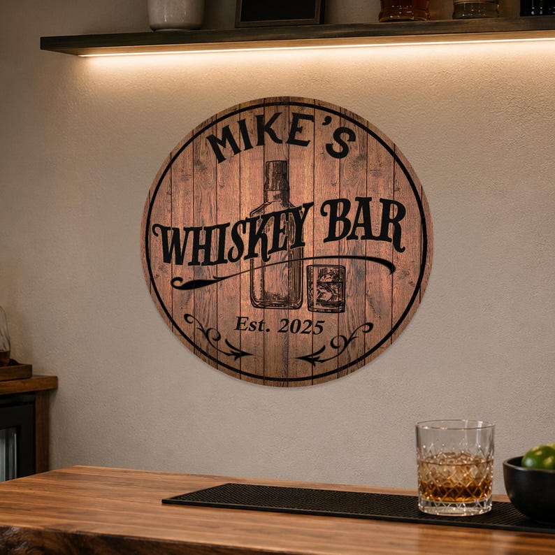 May include: Round wooden sign with the text "Mike's Whiskey Bar" in black lettering. The sign features an illustration of a whiskey bottle and a glass. The text "Est. 2025" is also included.
