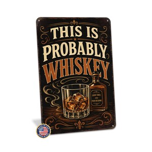 以下が含まれることがあります： 白と茶色の文字で「THIS IS PROBABLY WHISKEY」と書かれた長方形の金属看板。氷の入ったウイスキーグラスとボトルが描かれています。小さな「Made in USA」エンブレムが左下にあります。