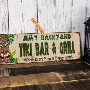 May include: A rustic metal sign with a tiki head and tropical leaves. The sign reads "Jim's Backyard Tiki Bar & Grill" and "Where Every Hour is Happy Hour!"