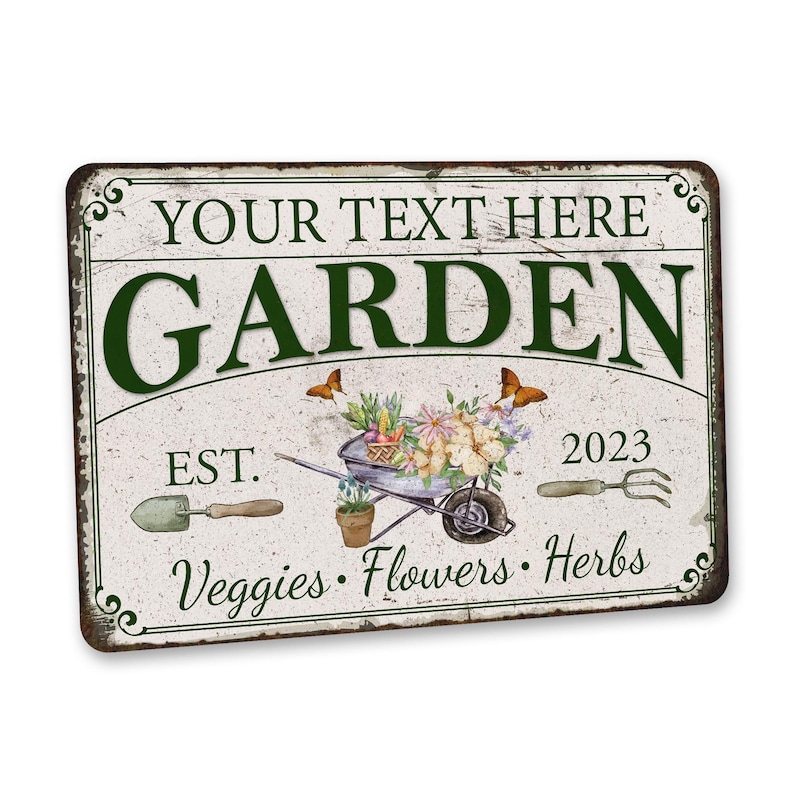 Peut inclure: Une pancarte en m&eacute;tal blanc avec du texte vert qui dit "YOUR TEXT HERE GARDEN EST. 2023 Veggies. Flowers. Herbs". La pancarte pr&eacute;sente une illustration de style vintage d'une brouette remplie de fleurs et de l&eacute;gumes, ainsi que des papillons et des outils de jardinage.