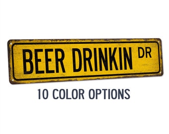May include: A yellow metal sign with black text that reads "BEER DRINKIN DR".