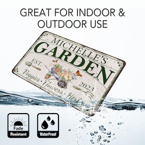 Peut inclure: Une plaque en m&eacute;tal blanc avec du texte vert qui dit "Michelle's Garden" avec une brouette pleine de fleurs et le texte "Est. 2023 Veggies Flowers Herbs". La plaque est partiellement immerg&eacute;e dans l'eau, avec une ic&ocirc;ne de soleil &eacute;tiquet&eacute;e "Fade Resistant" et une ic&ocirc;ne de goutte d'eau &eacute;tiquet&eacute;e "Waterproof" en dessous.