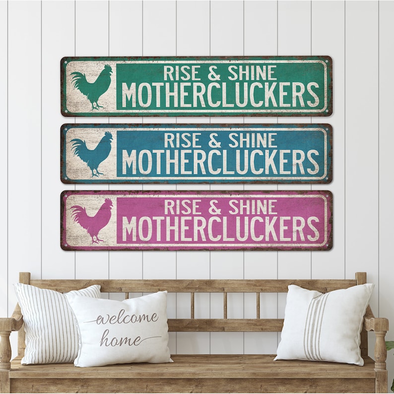 May include: Three rustic metal signs featuring a rooster silhouette and the text "Rise & Shine Mothercluckers" in white. The signs are in teal, blue, and pink.