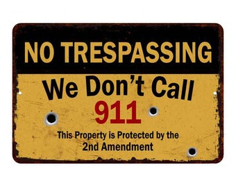 May include: A yellow metal sign with black lettering that reads "NO TRESPASSING We Don't Call 911 This Property is Protected by the 2nd Amendment". The sign has bullet holes and a distressed look.