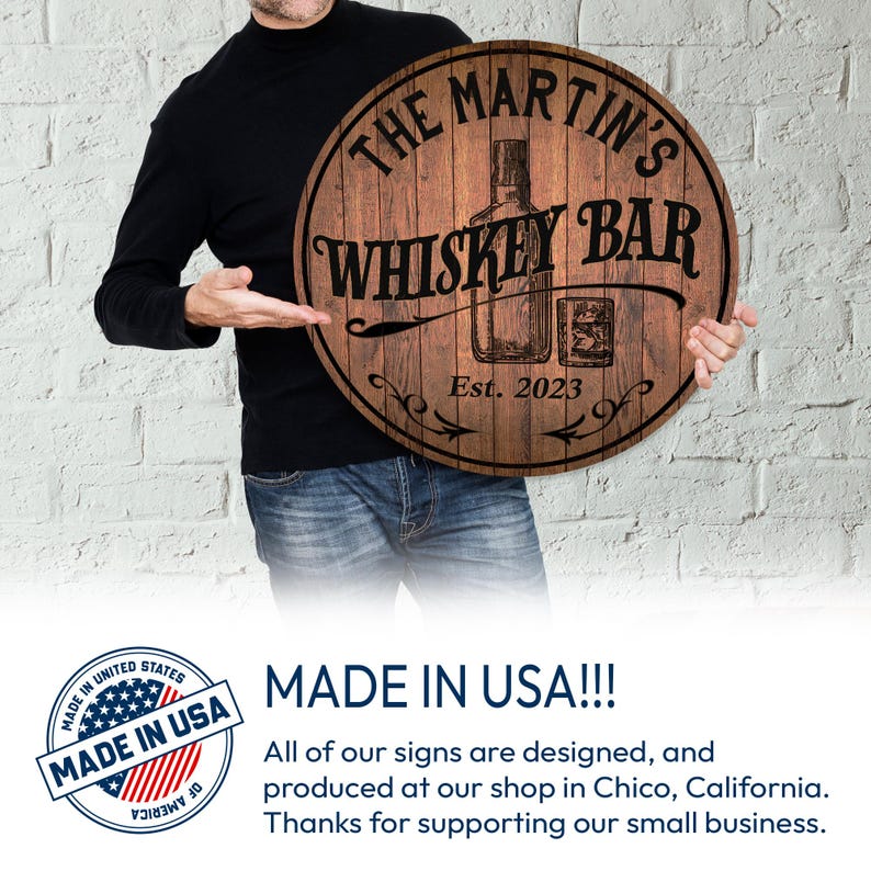 May include: A round wooden sign with the text "THE MARTIN'S WHISKEY BAR" and "Est. 2023" in black. The sign features an illustration of a whiskey bottle and a glass. The sign is held by a person.