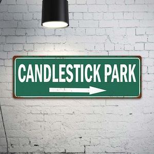 May include: A green metal sign with white text and a white arrow pointing to the right. The sign reads "CANDLESTICK PARK".
