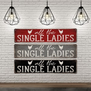 Pu&ograve; includere: Tre cartelli in legno rustico con una finitura usurata. Ogni cartello presenta una silhouette di pollo bianca e il testo "all the single ladies" in lettere bianche.