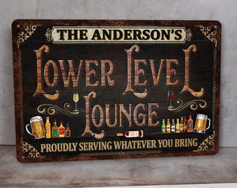May include: A personalized metal sign with a rustic woodgrain background. The sign reads "The Anderson's Lower Level Lounge" with a variety of drinks and bottles depicted below. The text "Proudly Serving Whatever You Bring" is at the bottom of the sign.