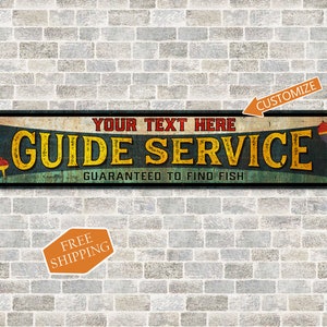 May include: A vintage-style metal sign with a blue, green, and yellow color scheme. The sign reads "GUIDE SERVICE" with the text "YOUR TEXT HERE" above and "GUARANTEED TO FIND FISH" below. The sign has a red and white fishing bobber on the right side. The sign is on a brick wall with a "FREE SHIPPING" label below.