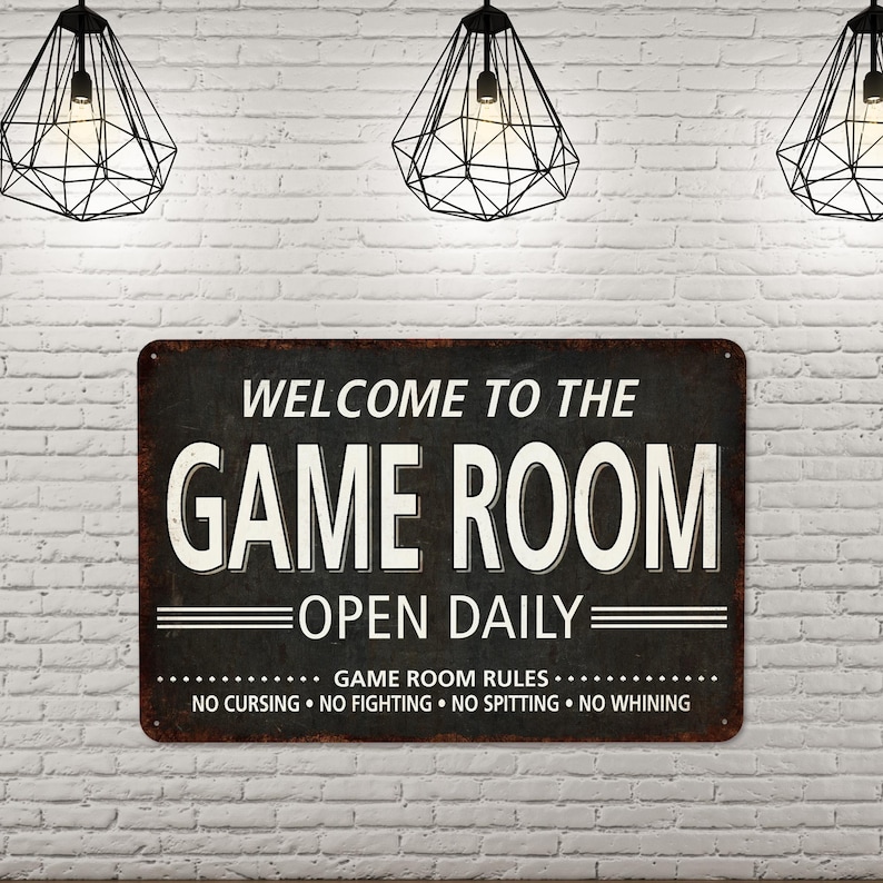 May include: A black and white metal sign with the text "Welcome to the Game Room Open Daily" and the rules "Game Room Rules: No Cursing, No Fighting, No Spitting, No Whining".