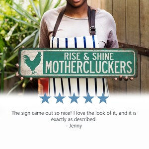 May include: A green and white metal sign with a rooster illustration and the text "RISE & SHINE MOTHERCLUCKERS".