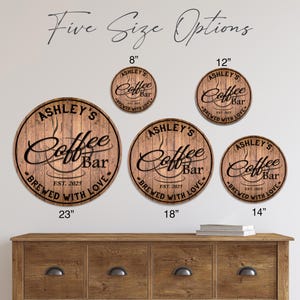 May include: Five round wooden signs with the text "Ashley's Coffee Bar" and "Brewed with Love." Sizes include 8", 12", 14", 18", and 23" diameter. The signs are brown with black lettering and a coffee cup graphic.