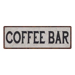 May include: A vintage-style metal sign with a white background and black text that reads "COFFEE BAR". The sign has a rusty brown border.
