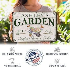 Peut inclure: Une plaque en m&eacute;tal blanc avec une finition vieillie comportant le texte "Ashley's Garden" en lettres vertes. La plaque comprend &eacute;galement le texte "Est. 2019" et "L&eacute;gumes, Fleurs, Herbes".