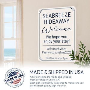 Op de afbeelding: Een rechthoekig wit metalen bord met een marineblauwe rand en de tekst "SEABREEZE HIDEAWAY Welcome". Het bord bevat wifi-informatie en een welkomstboodschap. Het bord hangt aan een muur bij een raam.