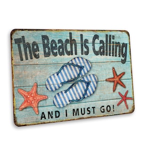May include: A blue and white wooden sign with the text "The Beach Is Calling And I Must Go!"  The sign features a pair of blue and white striped flip flops and three red starfish.