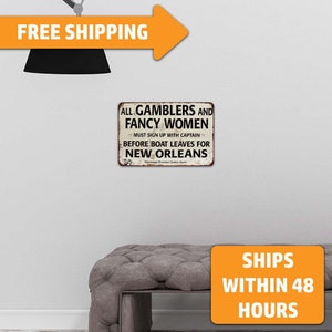 May include: A vintage-style metal sign with a distressed white background and black text. The sign reads "All Gamblers and Fancy Women Must Sign Up With Captain Before Boat Leaves For New Orleans".
