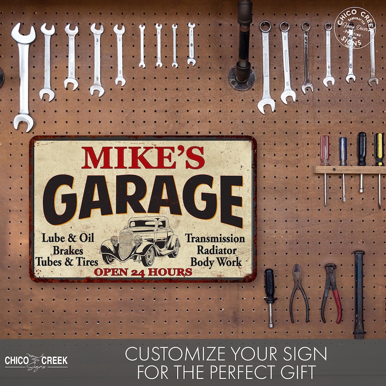 May include: A vintage-style metal sign with the text "MIKE'S GARAGE" in red and black lettering. The sign features a cartoon image of a classic car and lists services offered, including "Lube & Oil", "Brakes", "Tubes & Tires", "Transmission", "Radiator", and "Body Work". The sign also states "OPEN 24 HOURS".