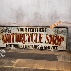 May include: A vintage-style metal sign with a distressed white background and red text that reads "Motorcycle Shop". The sign also features two black and white motorcycle illustrations and the text "Your Text Here" and "Motorbike Repairs & Service".