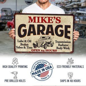 May include: A vintage-style metal sign with the text "MIKE'S GARAGE" in red and black lettering. The sign features a black and white illustration of a classic car and lists services offered, including "Lube & Oil", "Brakes", "Tubes & Tires", "Transmission", "Radiator", and "Body Work". The sign also states "OPEN 24 HOURS".