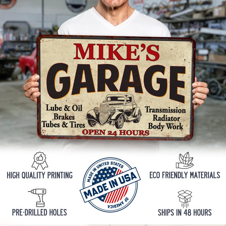May include: A vintage-style metal sign with the text "MIKE'S GARAGE" in red and black lettering. The sign features a black and white illustration of a classic car and lists services offered, including "Lube & Oil", "Brakes", "Tubes & Tires", "Transmission", "Radiator", and "Body Work". The sign also states "OPEN 24 HOURS".