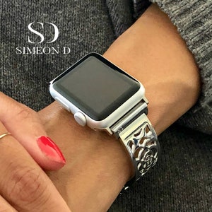 May include: Silver Apple Watch with a silver, ornate, rose-shaped band.