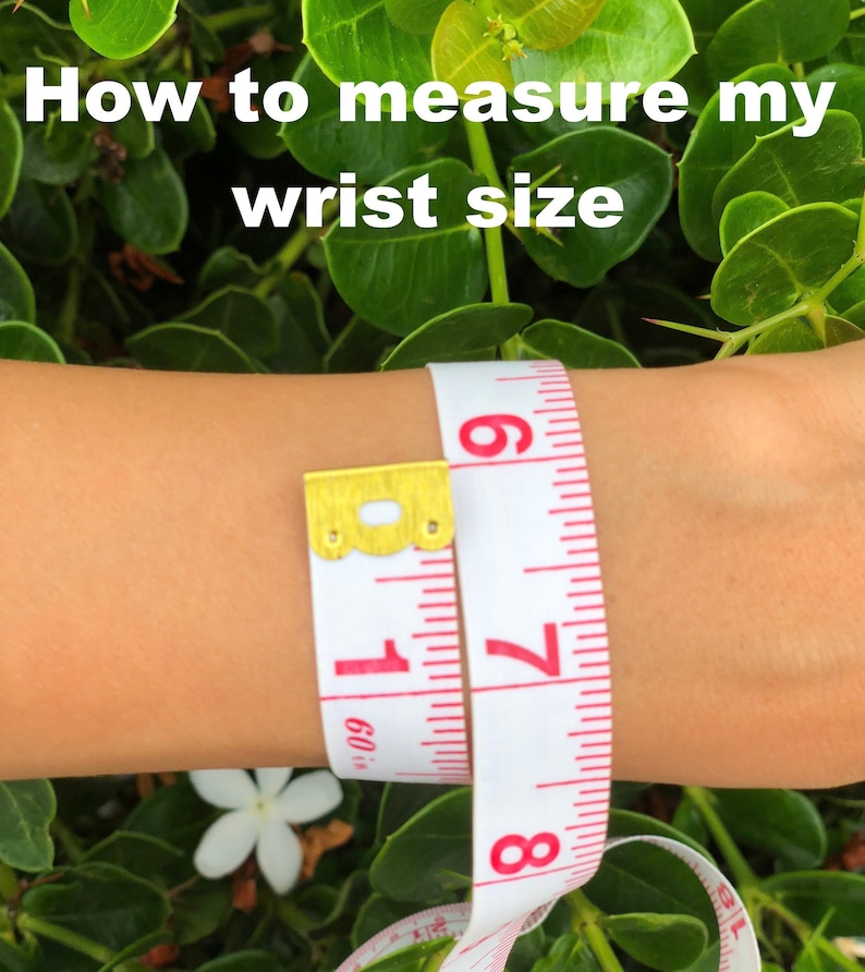 May include: A white tape measure with red markings is wrapped around a person's wrist. The tape reads 7 and 8 inches.