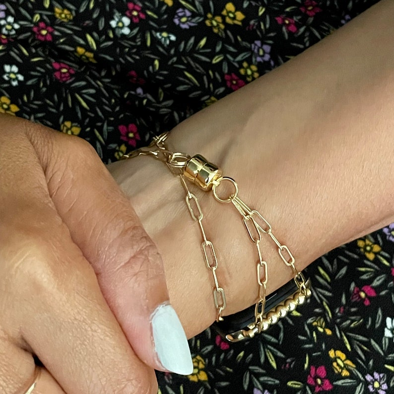 Puede incluir: Un brazalete de cadena dorada con cierre magn&eacute;tico. El brazalete est&aacute; formado por tres cadenas de diferentes longitudes.