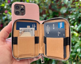 May include: A pink leather phone case with a zippered wallet attached. The wallet has multiple card slots and a cash pocket. The wallet is open and shows a credit card, a $100 bill, and a Marriott Bonvoy Business card.