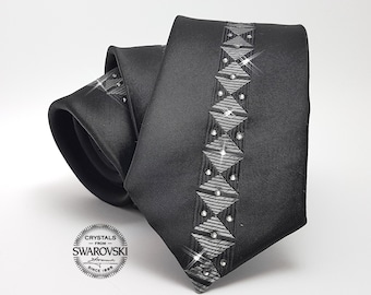 Könnte beinhalten: Schwarze Seidenkrawatte mit silberfarbenem geometrischem Muster und Kristallen von Swarovski. Die Krawatte trägt ein Etikett mit der Aufschrift "Crystals from Swarovski" und "Since 1895".