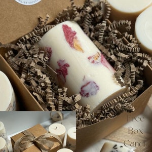 May include: A set of four candles in a brown box with a label that says "Aga Makes Candles". The candles are white and have different floral designs. The box is filled with brown packing paper. There is a free box candle with a lavender design.