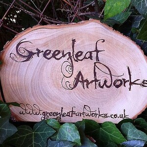 May include: A wooden sign with the text "Greenleaf Artworks" and the website address "www.greenleafartworks.co.uk" burned into the surface.