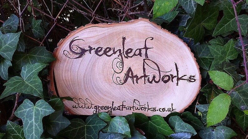 May include: A wooden sign with the text "Greenleaf Artworks" and the website address "www.greenleafartworks.co.uk" burned into the surface.