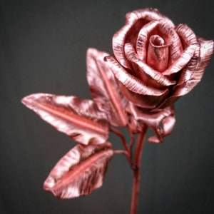 May include: A rose made of metal with a copper finish. The rose is a single bloom with leaves and a stem.