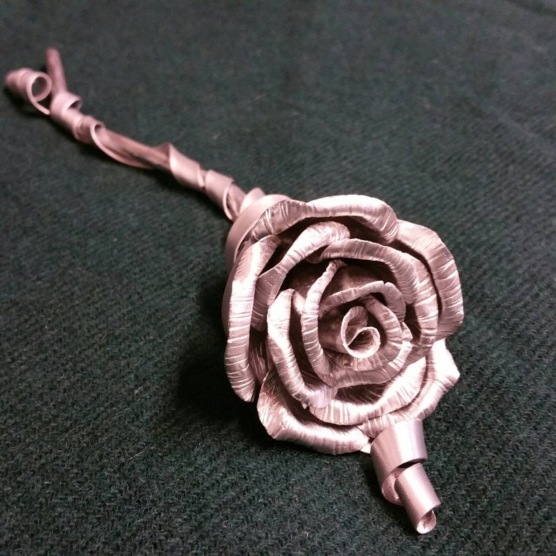 May include: A silver metal rose with a stem made of twisted metal.
