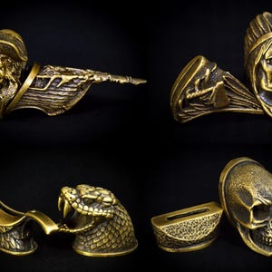 以下が含まれることがあります： 金属製の装飾的な剣の柄が4つ。柄は真鍮製で、骸骨、蛇、ネイティブアメリカンの酋長、海賊など、さまざまなデザインが施されています。