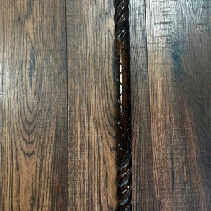 Puede incluir: Un bast&oacute;n de madera marr&oacute;n oscuro con un dise&ntilde;o retorcido y una parte superior de lat&oacute;n.