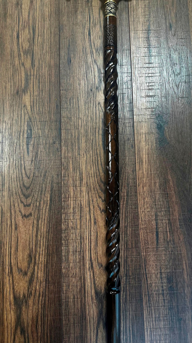 Puede incluir: Un bast&oacute;n de madera marr&oacute;n oscuro con un dise&ntilde;o retorcido y una parte superior de lat&oacute;n.