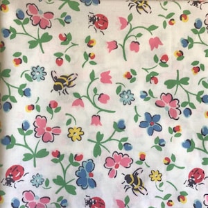 Pode incluir: Tecido branco com um padrão repetido de flores rosa e azuis, vinhas verdes, joaninhas e abelhas. O design floral inclui pequenos detalhes amarelos e vermelhos. A estética geral lembra um estilo vintage ou cottagecore.