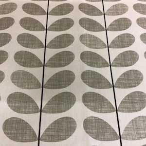 Puede incluir: Una tela blanca con un patrón repetido de formas de hojas verdes. Las hojas son estilizadas y tienen una apariencia texturizada.