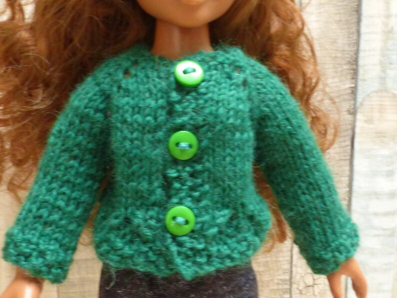 May include: A green knitted cardigan with four green buttons. The cardigan is made of a soft, fuzzy yarn.